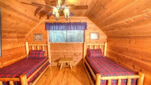 A cabin with two wooden beds, a small table, and a ceiling fan. - Fox Ridge- Perfect cabin nestled in the woods with a large stacked rock firepit (Sautee Nacoochee)
