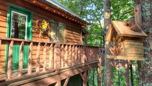 A wooden cabin with a balcony and a birdhouse attached to a tree. - Fox Ridge- Perfect cabin nestled in the woods with a large stacked rock firepit (Sautee Nacoochee)