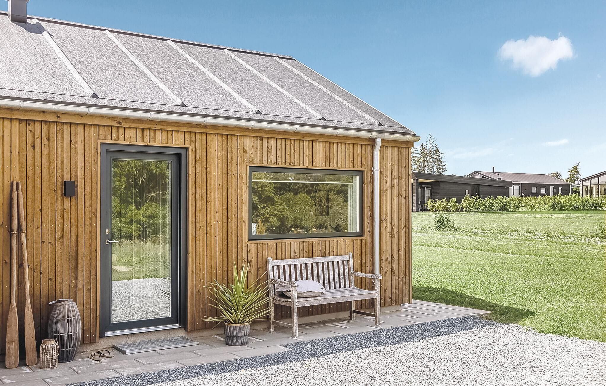 Une cabane en bois avec une grande fenêtre, un banc et une porte.