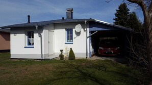 A single-story house with a garage, a satellite dish, and a red car parked inside. - Holiday house Blue Salon (Karlshagen)