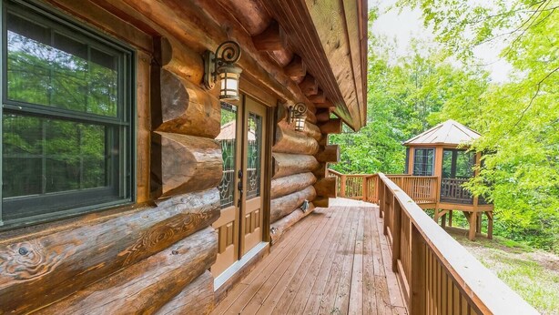 A log cabin with a wooden deck and a small wooden structure in the background. - Ridge Views - 2BR/New Hot Tub/New Firepit/Grill/Sleeps 8 (Gatlinburg)