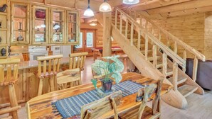 A wooden interior with a staircase, dining area, and kitchen. - Ridge Views - 2BR/New Hot Tub/New Firepit/Grill/Sleeps 8 (Gatlinburg)