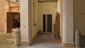 Un estrecho callejón con una puerta al final, plantas en macetas y un pilar de piedra.