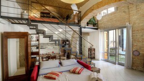 Un dormitorio amplio con una cama grande, una escalera que sube a un nivel superior y vistas al exterior a través de amplios ventanales.