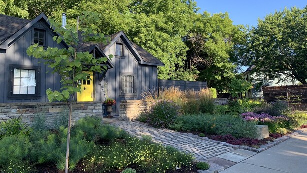 A two-story house with a stone foundation, a yellow front door, and a brick pathway leading to the entrance. - Charming Carriage House in Niagara's Wine Country (Niagara Falls)