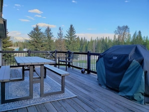 Enjoy al fresco dining with a view of the surrounding forest and mountains from this outdoor deck, featuring a picnic table, chairs, and grill.