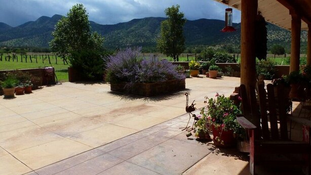Un porche techado con vistas a montañas, plantas en macetas y un banco de madera rústica.