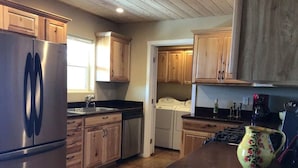 Una cocina con gabinetes de madera, un refrigerador de acero inoxidable, un fregadero, una estufa y un jarro con motivos florales sobre la encimera.