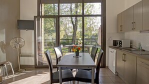 Une cuisine moderne avec un coin repas, de grandes fenêtres et une vue sur les arbres.
