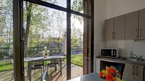 Une cuisine moderne avec un coin repas, de grandes fenêtres et une vue sur un jardin.