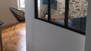 Ein Zimmer mit einer Steinswand, Holzboden, einem schwarzen Sessel und einem blauen Sofa.