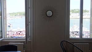 Ein Zimmer mit Blick auf einen Hafen, einer Wanddekoration mit Sonnenstrahlen und einem Sessel.