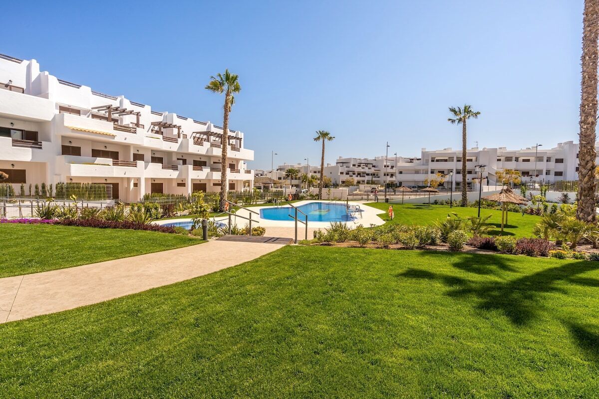 Un hôtel doté d’une piscine, de palmiers et d’une pelouse bien entretenue.