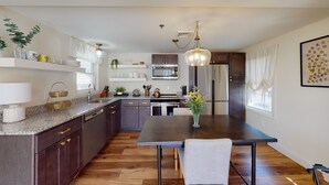 Una cucina moderna con mobili in legno scuro, un piano di lavoro in granito, elettrodomestici in acciaio inossidabile e un'area pranzo con tavolo e sedie scure.