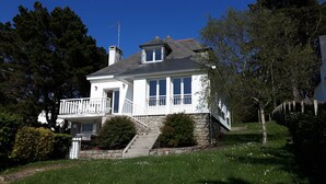 A two-story house with a balcony, stone steps, and a stone chimney.