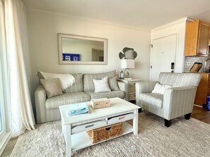 Un salon comprenant un canapé, un fauteuil, une table basse et un miroir au mur.