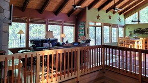 A spacious room with a wooden ceiling and large windows, a seating area with a couch and chairs, and a dining table with chairs. - Meadows Hideaway with Access to Exclusive Golf (Sunriver)