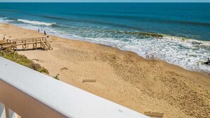 A beach with a wooden walkway leading to the water, clear skies, and calm waves. - Take It E-Sea | Oceanfront + Community Pool! (Kure Beach)