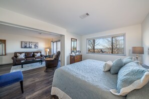 A bedroom with a large bed, a desk, a chair, and a sofa.