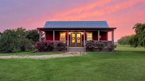 A red house with a porch, a front door, and a wreath on the door.