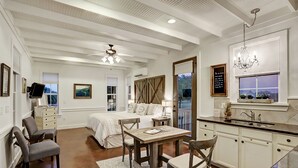 A spacious bedroom with a large bed, a desk with chairs, and a view of the outdoors.