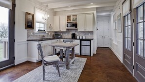 A kitchen with white cabinets, a wooden table, and a chandelier.