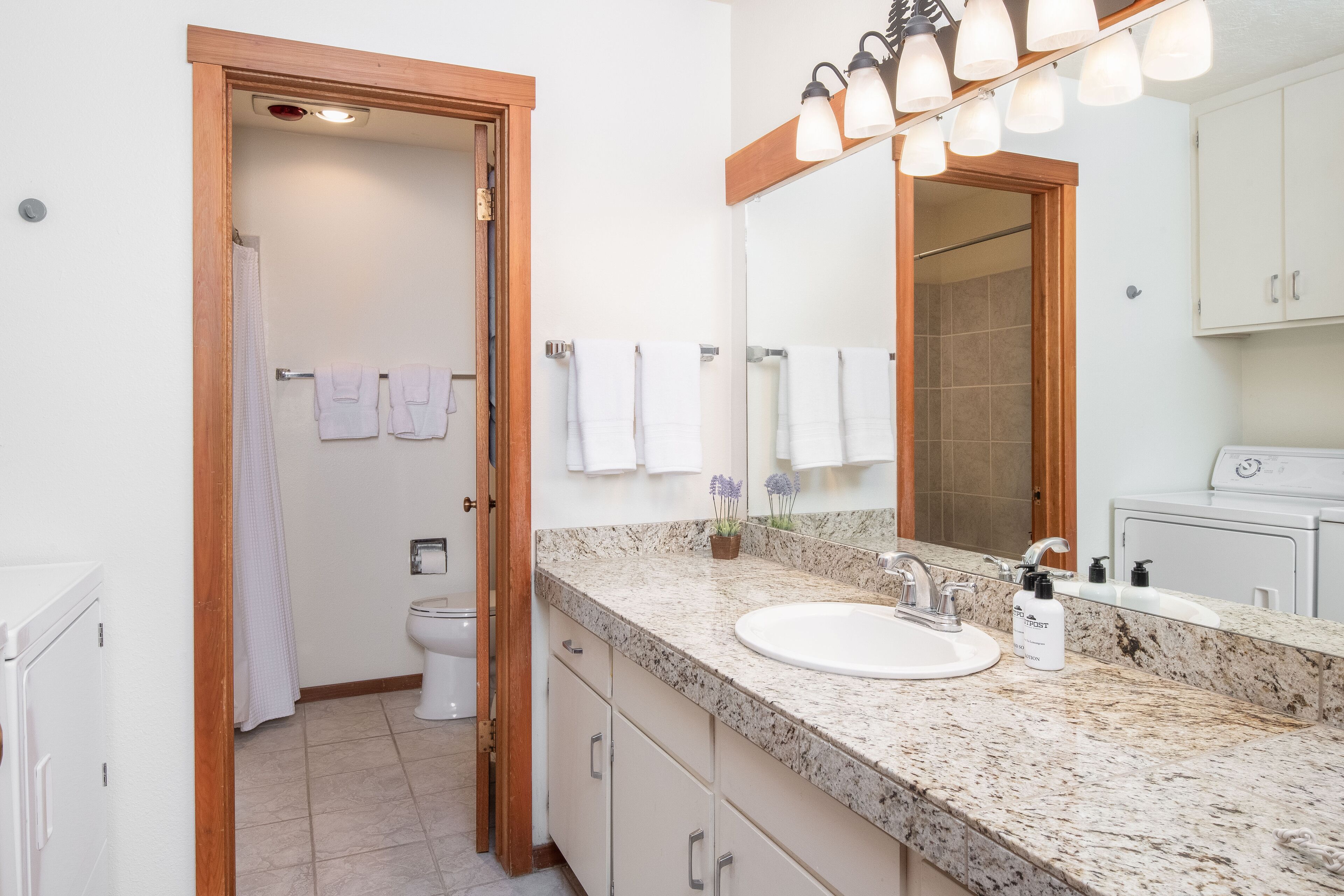 A bathroom with a sink, mirror, towel rack, and a shower area.