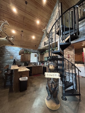 Staircase leads to an upper level, featuring a rustic wooden interior with a bear sculpture.