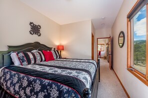 Une chambre avec deux lits, une table de chevet, une lampe, un miroir et une vue sur l’extérieur.