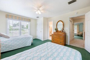 A bedroom with two beds, a dresser, a ceiling fan, and a window with blinds. - The Colman at Ships Watch in Duck (Duck)