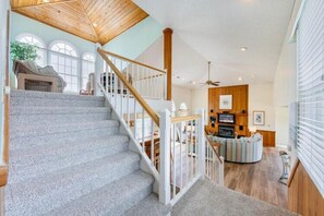 A staircase leading to a living area with a fireplace, a television, and a ceiling fan. - The Colman at Ships Watch in Duck (Duck)