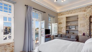 Une chambre avec un grand lit, une télévision, un canapé et un mur en pierre.