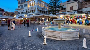 Une place publique avec une fontaine, des espaces de repos en plein air et des boutiques.