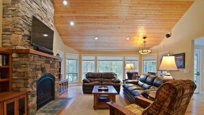 A spacious living room with a stone fireplace, leather sofas, and a wooden ceiling. - Sunriver Golf Retreat with Access to Exclusive Golf (Bend)