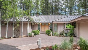 A modern house with a paved driveway, wooden fences, and a well-maintained garden with various plants and shrubs. - Sunriver Golf Retreat with Access to Exclusive Golf (Bend)