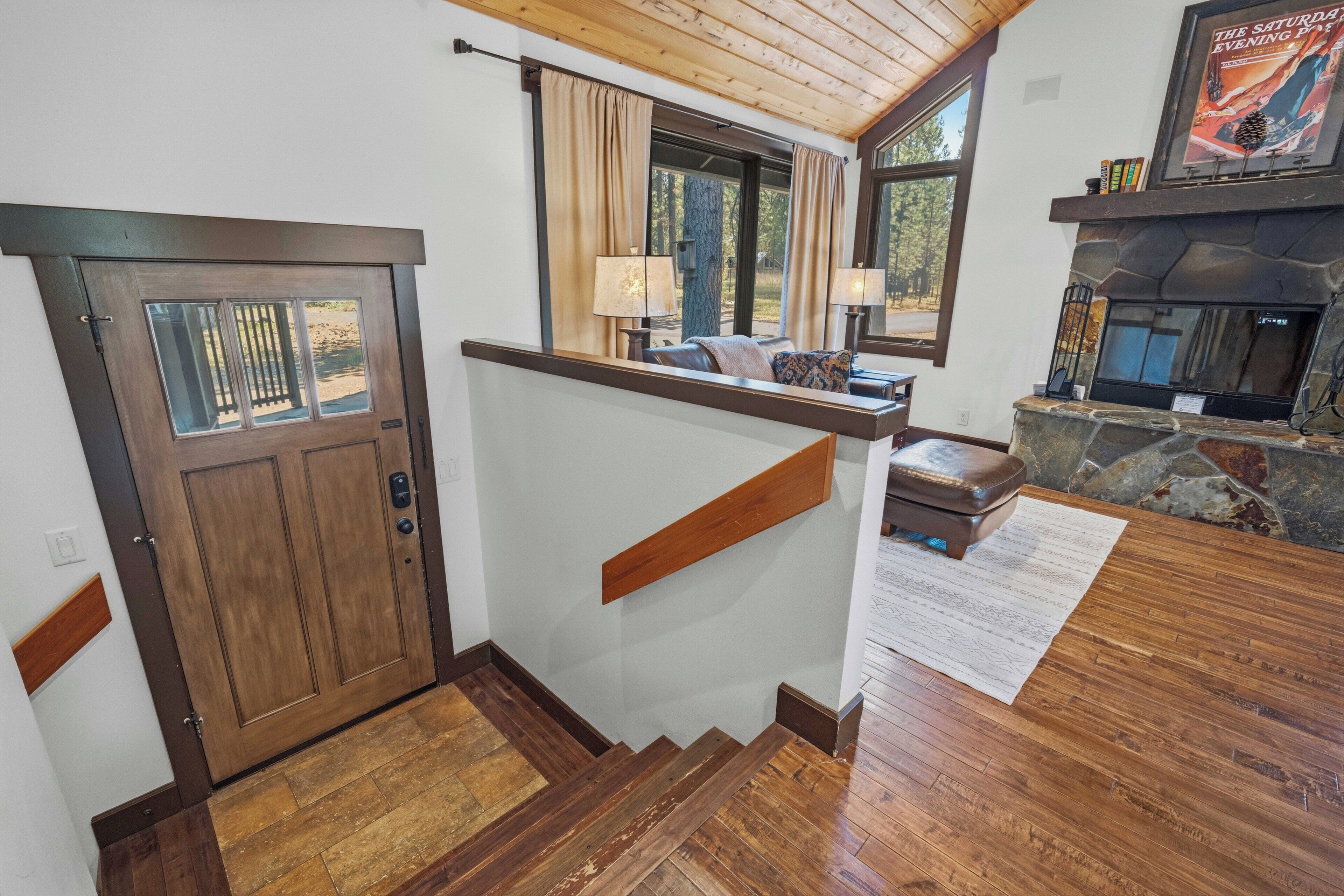 A wooden staircase leading to a living area with a fireplace, a sofa, and a lamp.