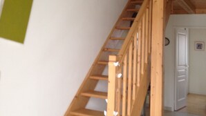 A wooden staircase with a handrail leading to a second-floor landing. - INDIVIDUAL HOUSE 110 m2 (ground floor + upper floor) CLOSED GARDEN. GARAGE + outdoor parking (Olonne-sur-Mer)