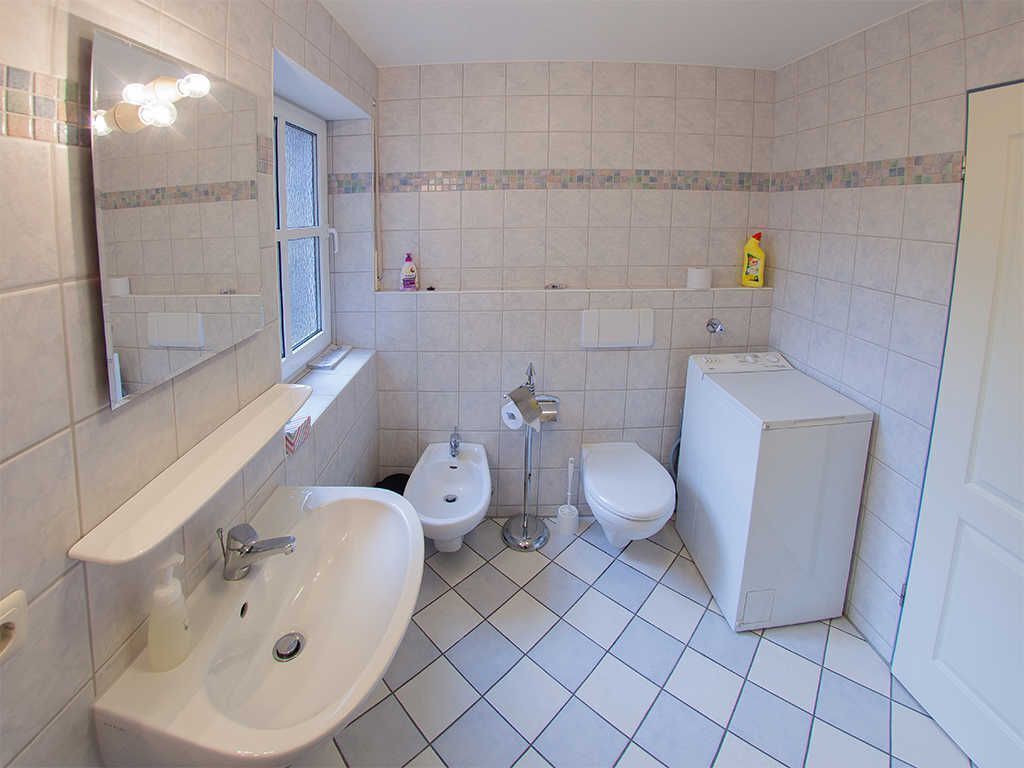 A bathroom with a sink, bidet, toilet, and a mirror.