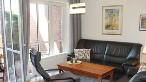 Ein Wohnzimmer mit einem schwarzen Ledersofa, einem Holztisch und einem schwarzen Sessel.