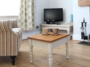 Relax in this inviting living room with a striped armchair, flat-screen TV, and comfortable coffee table.