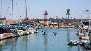 Un port de plaisance avec des bateaux, un phare et un bâtiment doté d’un toit rouge.