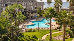 Un complexe hôtelier doté d’une piscine, de palmiers et offrant une vue sur l’océan.