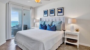A bedroom with a large bed, a ceiling fan, a view of the ocean, and framed starfish pictures on the wall. - Silver Beach 404 | OBA Beach front condo! Pet Friendly! (Orange Beach)
