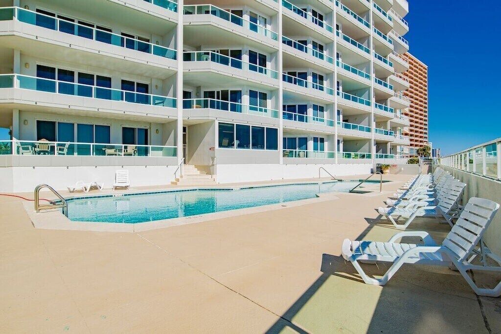 Un hôtel à plusieurs étages doté d’une piscine et de chaises longues.