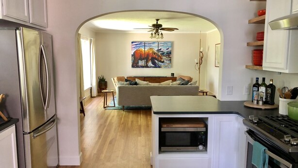 Eine moderne Küche mit integriertem Mikrowellenherd, Backofen und Kühlschrank. Es gibt eine Essecke mit einer Couch und einem Gemälde an der Wand.