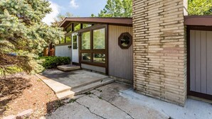 Una casa moderna con chimenea de ladrillo, ventanas amplias y un jardín cuidado.