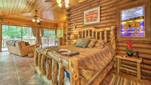 Un dormitorio tipo cabaña de troncos con una cama grande, cabecera de madera y vistas al exterior.