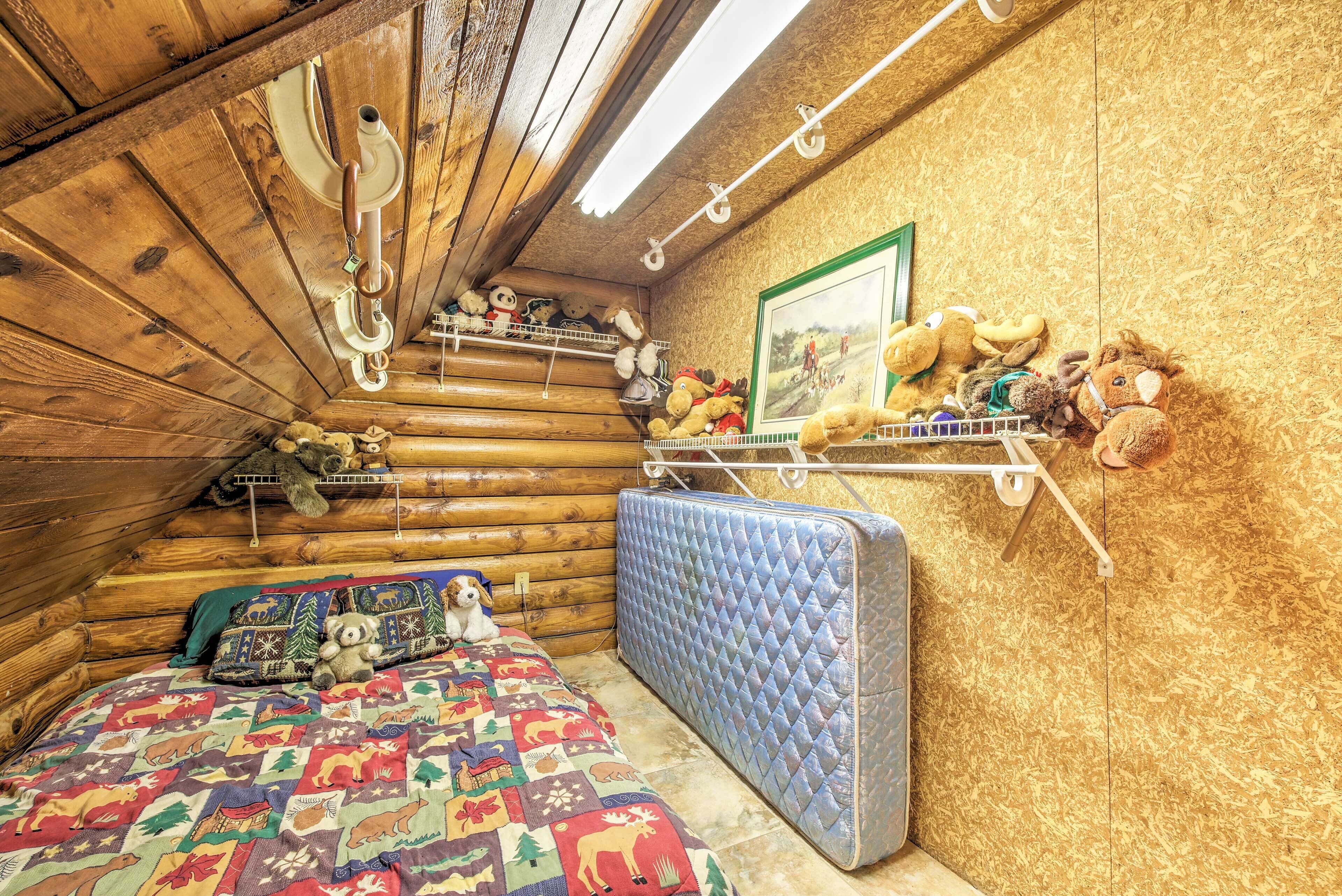 Ein gemütliches Blockhauszimmer mit einem Bett, einer Matratze und einem Regal mit Stofftieren.