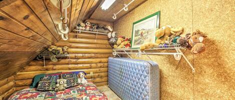 Ein gemütliches Blockhauszimmer mit einem Bett, einer Matratze und einem Regal mit Stofftieren.