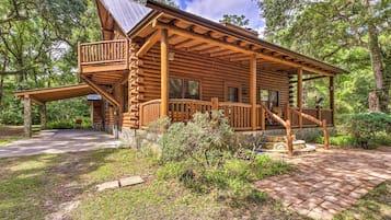 Step into this charming cabin, surrounded by lush greenery and trees, with a spacious porch and a large window offering a view of the surrounding landscape.
